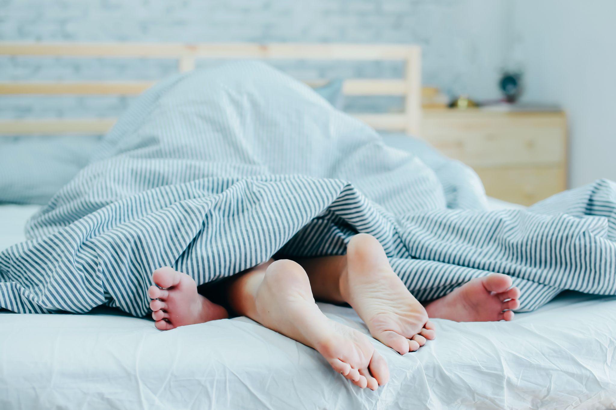 feet of a couple under the covers in bed - intimacy, dryness, and painful sex during menopause
